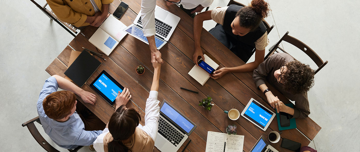 People shaking hands People in a meeting room with laptops